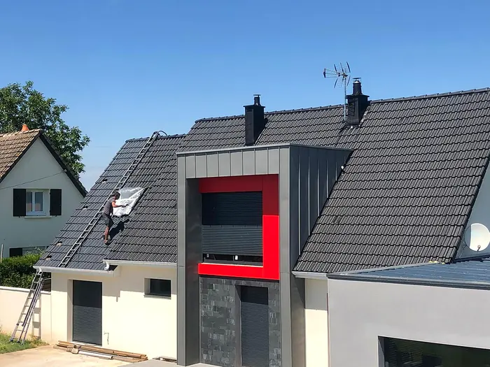 Couvreur sur une toiture sombre avec encadrement en zinc