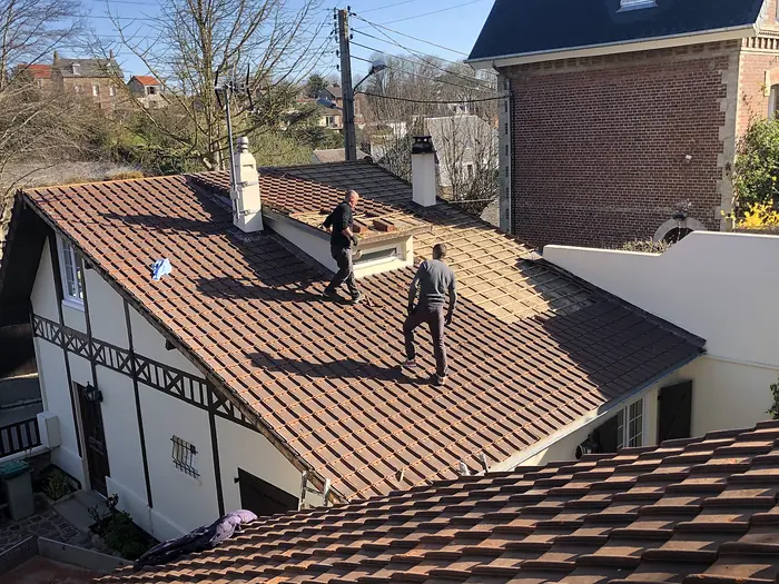 Deux couvreurs travaillant sur une toiture de maison à colombages